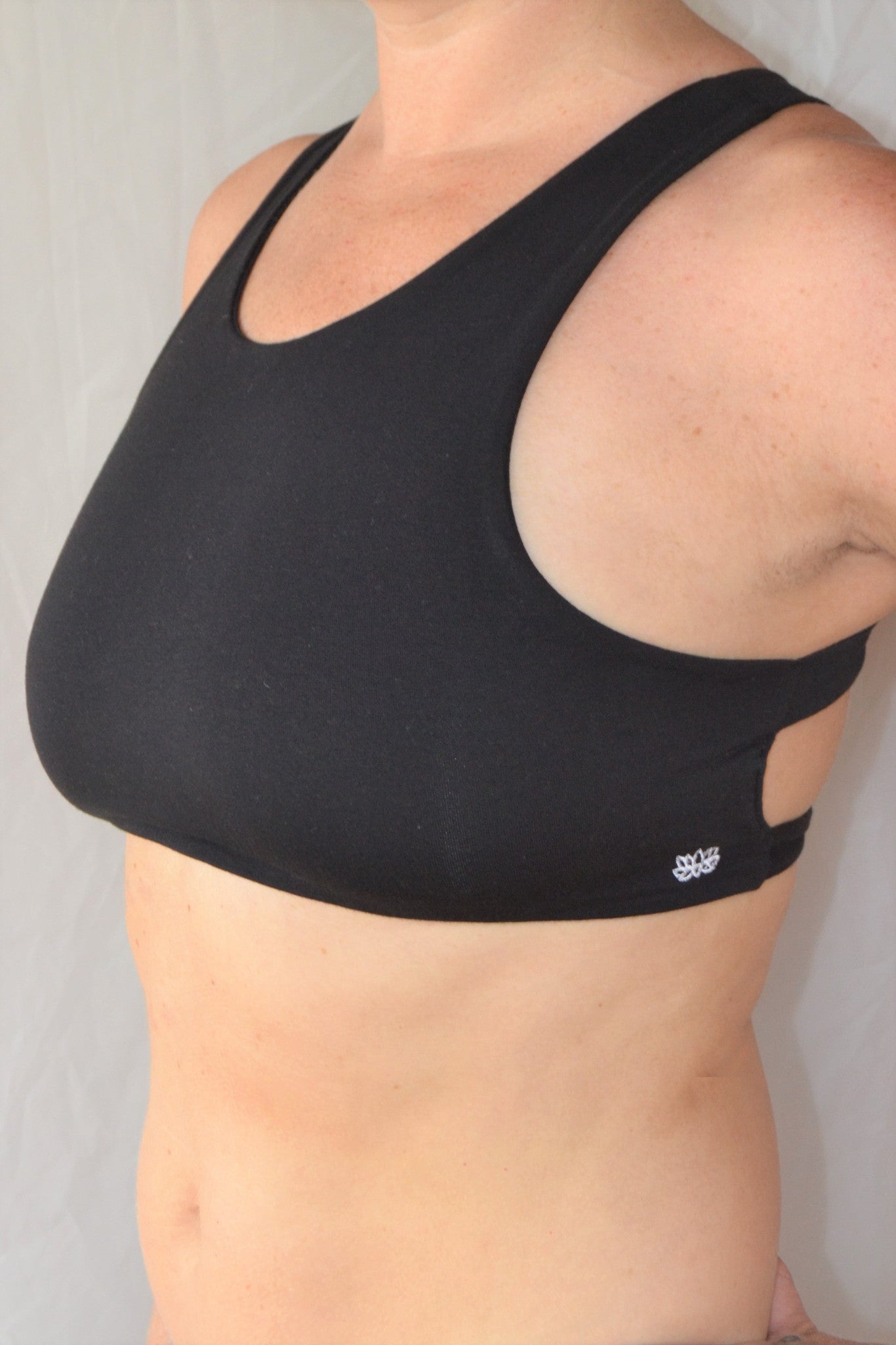 Solid black yoga crop top bra that accentuates the natural beauty of a woman's back with light support and lace up corset back, perfect for festival season.