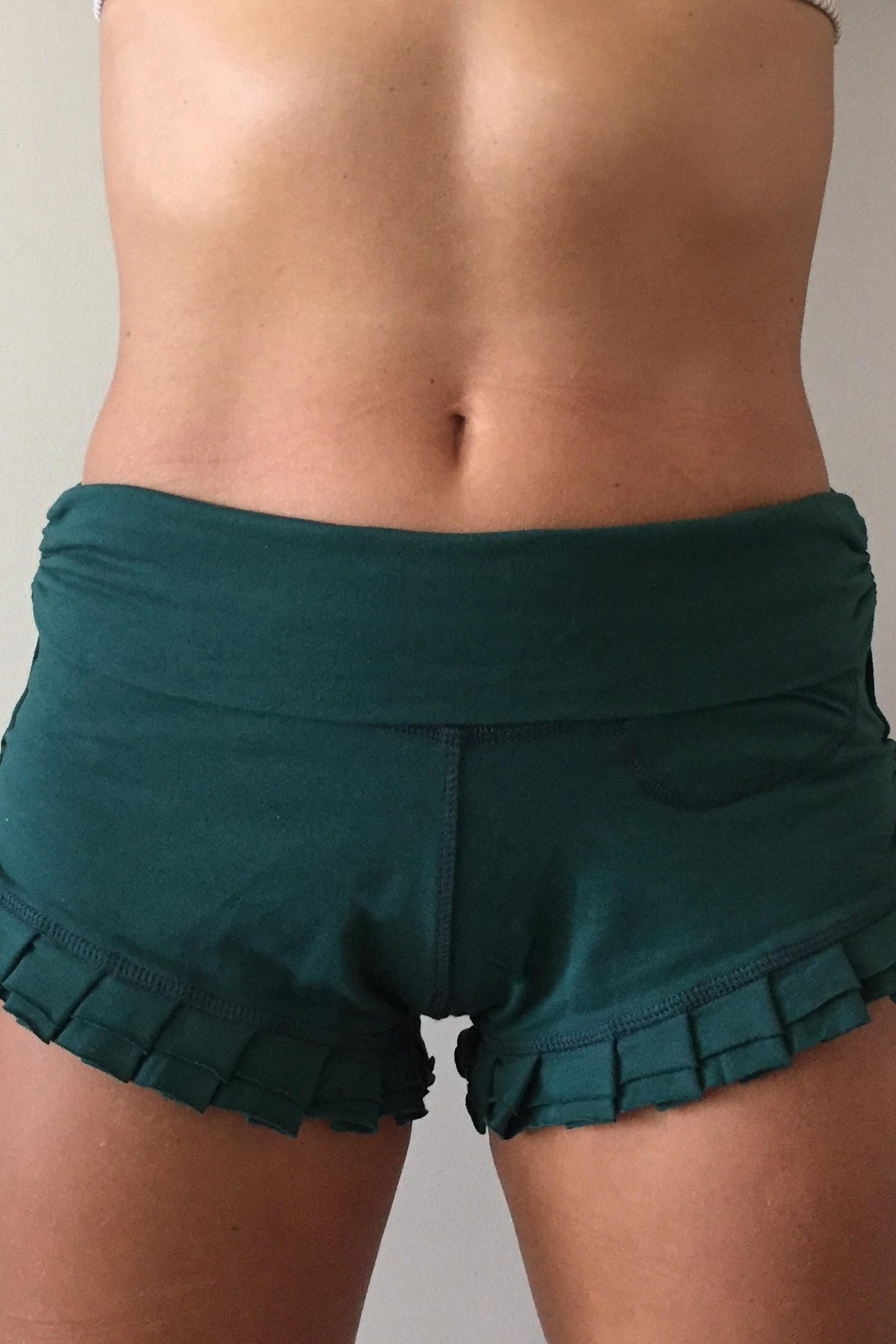 Front view of Forest green shorts with ruffles at bottom and fold over waist perfect for hot yoga or paired with your favorite top, also great for under a short dress.
