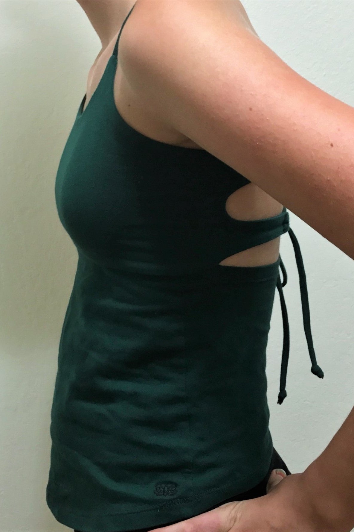 Side view of Tie Back Tank in Forest green has small black lotus flower embroidery on bottom left side.