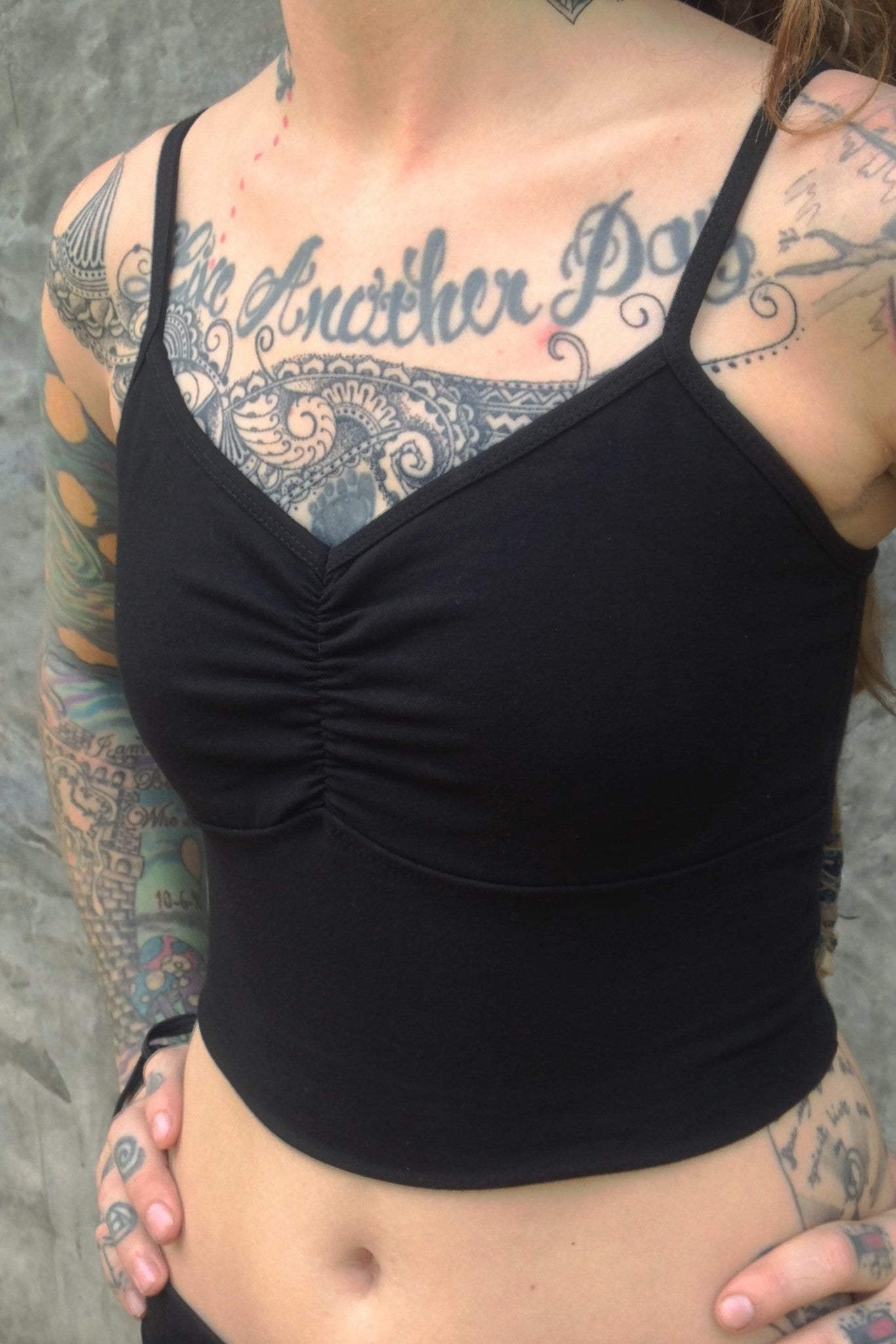 Side view of black Onyx Blissed Out Crop Tank by Lotus Tribe with adjustable spaghetti straps and scrunched center puckering between the breasts. Made from 90% Organic Cotton with 10% Spandex.