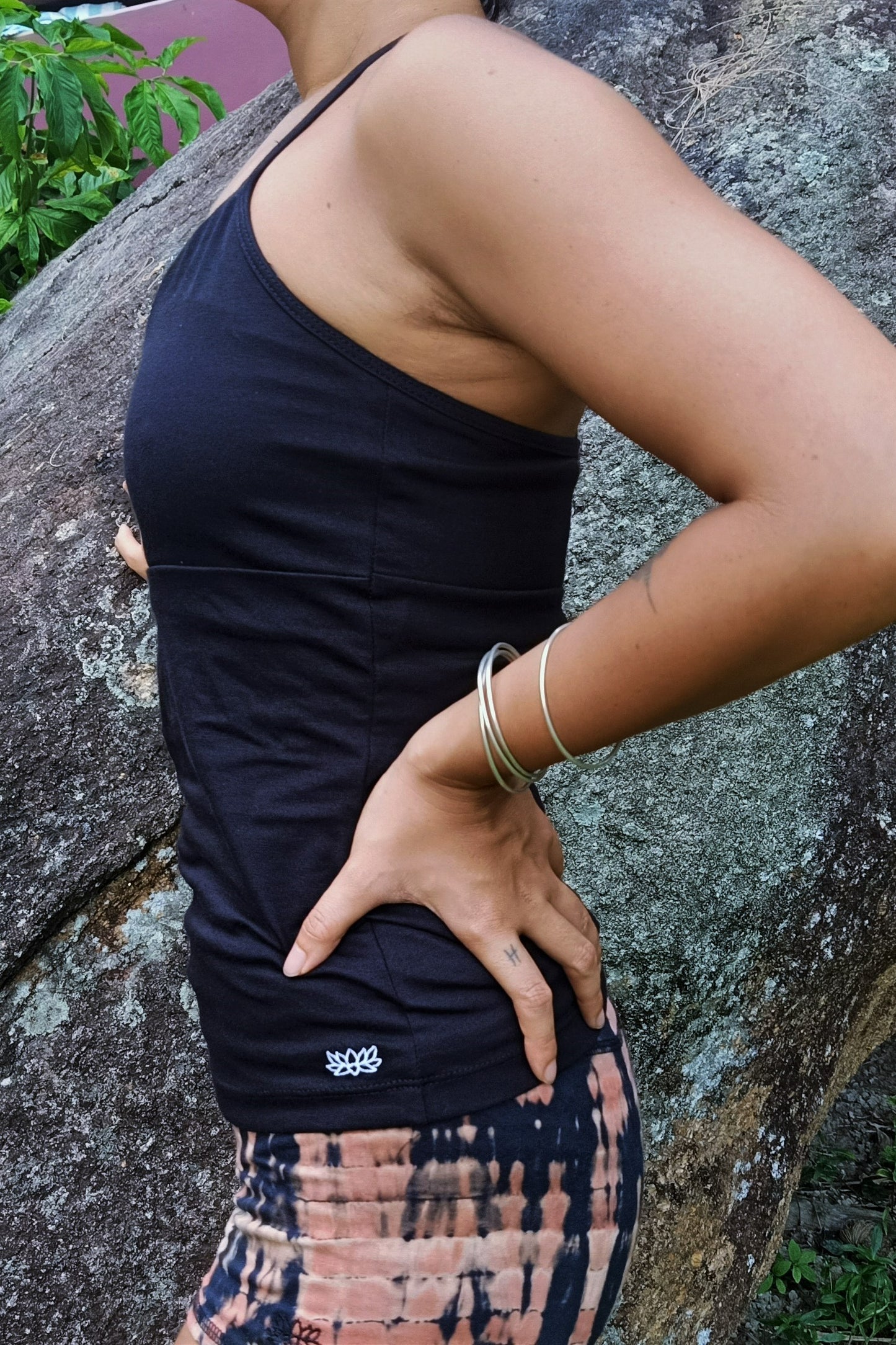 Side view of Onyx Ananda Tank shows small white lotus flower embroidery on bottom of left side.