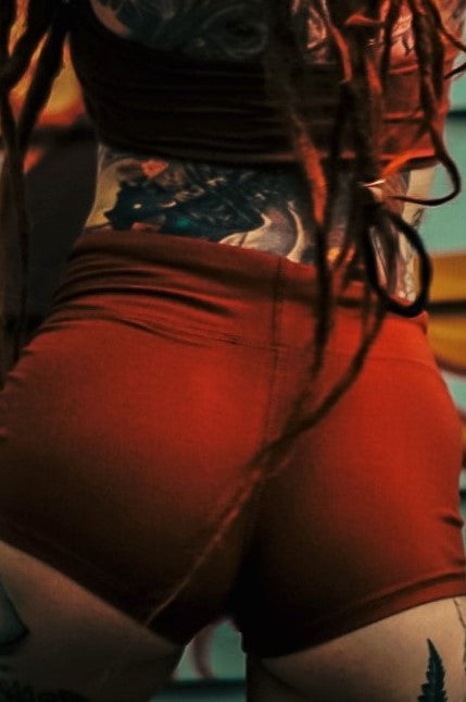 Back view of Rust colored Yoga Shorts with fold top waist that can be worn high waisted. Booty hugging short shorts.