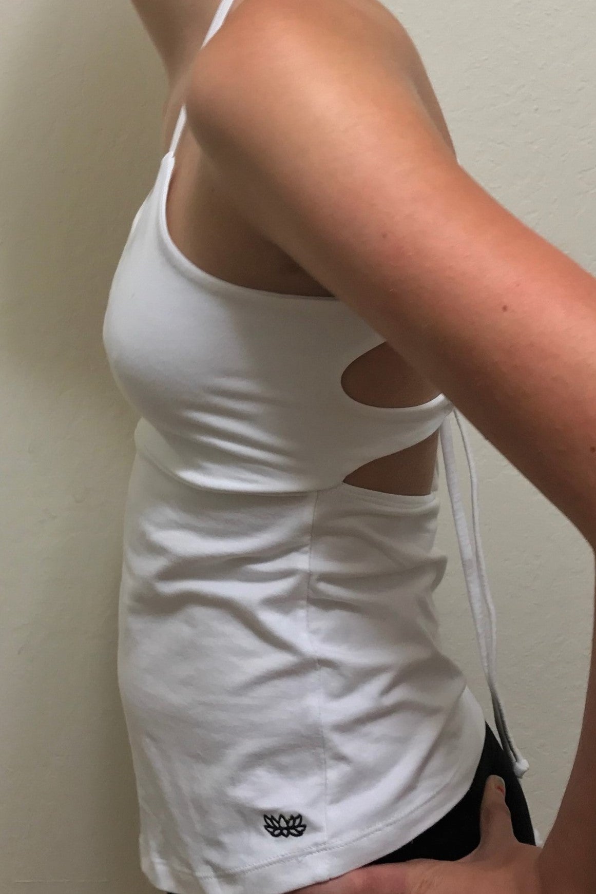Side view of Snow Tie Back Tank show small black lotus flower embroidery on bottom left side.