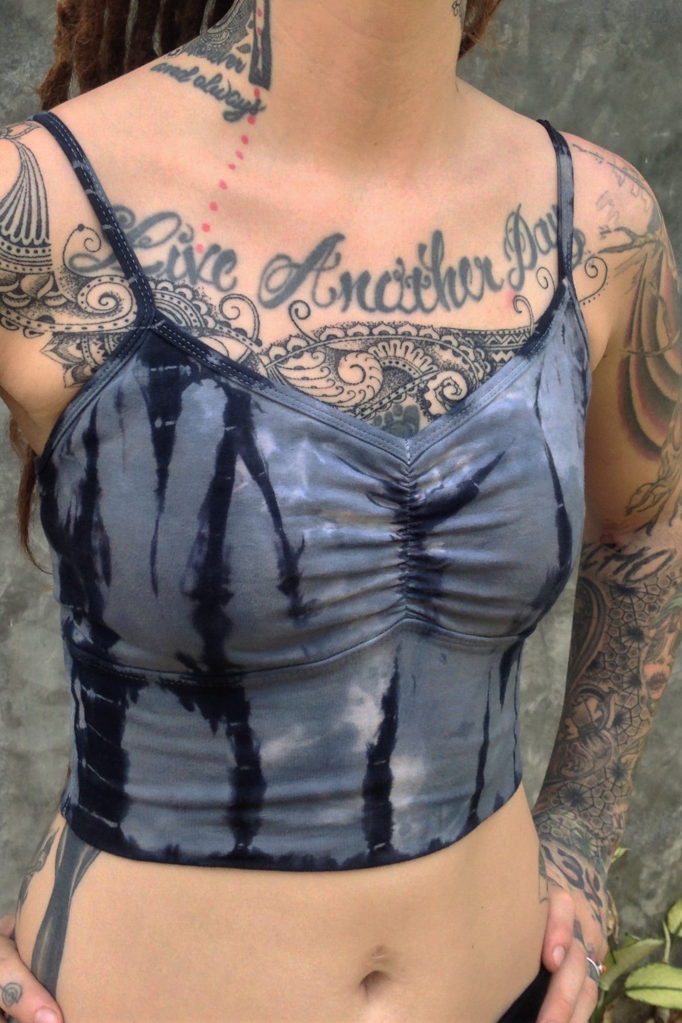 Side view of Sodalite tie dye Blissed Out crop tank with adjustable spaghetti straps and scrunched center puckering between the breasts. Steel blue with black streaks and white highlights. 90% Organic cotton with 10% spandex