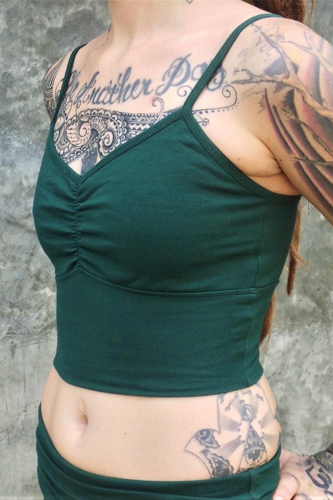 Side view of Forest green Blissed Out Crop Tank by Lotus Tribe with adjustable spaghetti straps and scrunched center puckering between the breasts. Made from 90% Organic Cotton with 10% Spandex. 