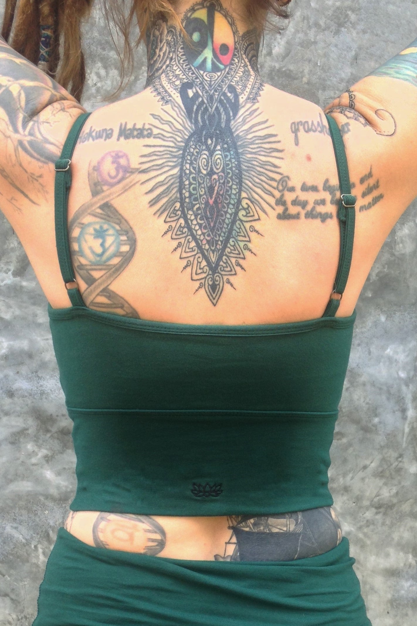 Back view of Blissed Out Crop Tank with adjustable spaghetti straps in solid Forest green with small Lotus Flower embroidery on center bottom of back. 