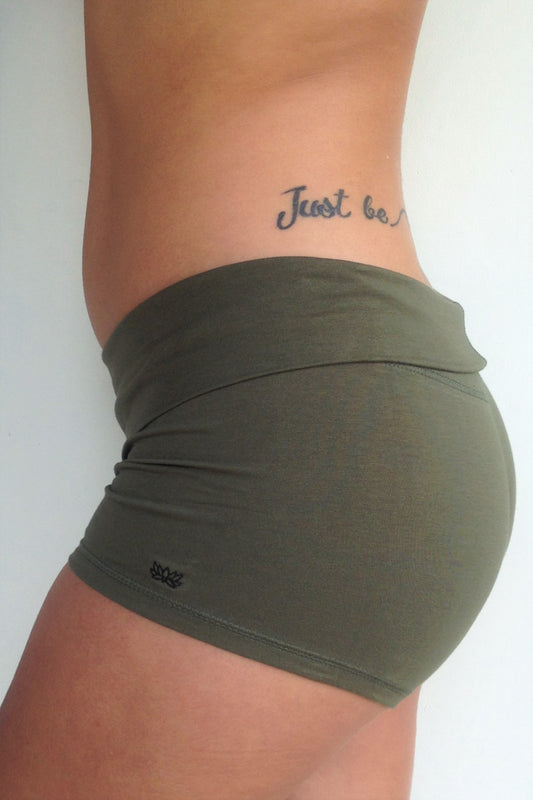 Side view of solid Sage green yoga shorts with fold over waist, can be worn higher waisted, or low on the hips. Small black Lotus Flower embroidery. 90% cotton 10% spandex.